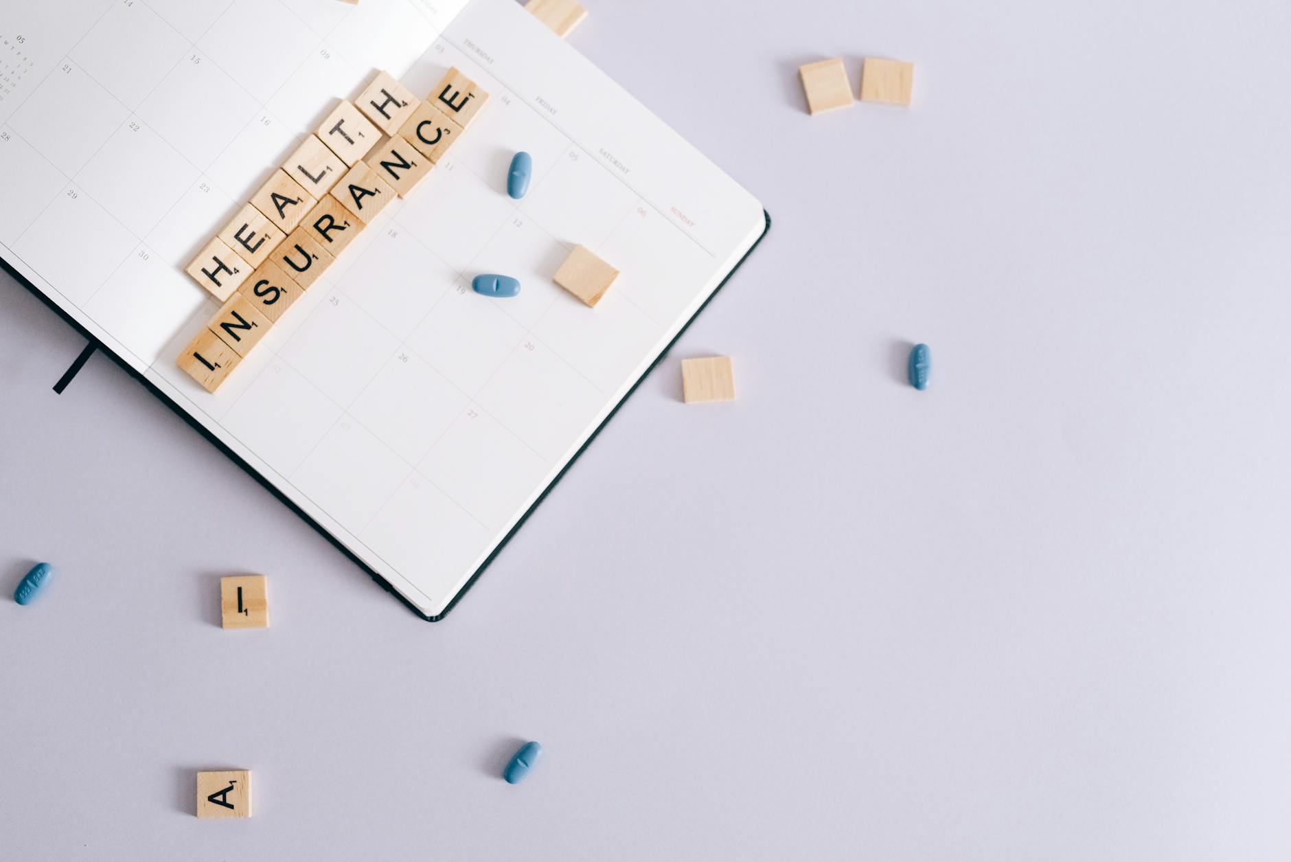 Flat lay of health insurance concept with planner and pills. (Photo by Leeloo The First on Pexels)