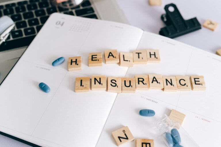 Scrabble tiles spelling 'Health Insurance' on planner with pills and laptop, symbolizing healthca... (Photo by Leeloo The First on Pexels)