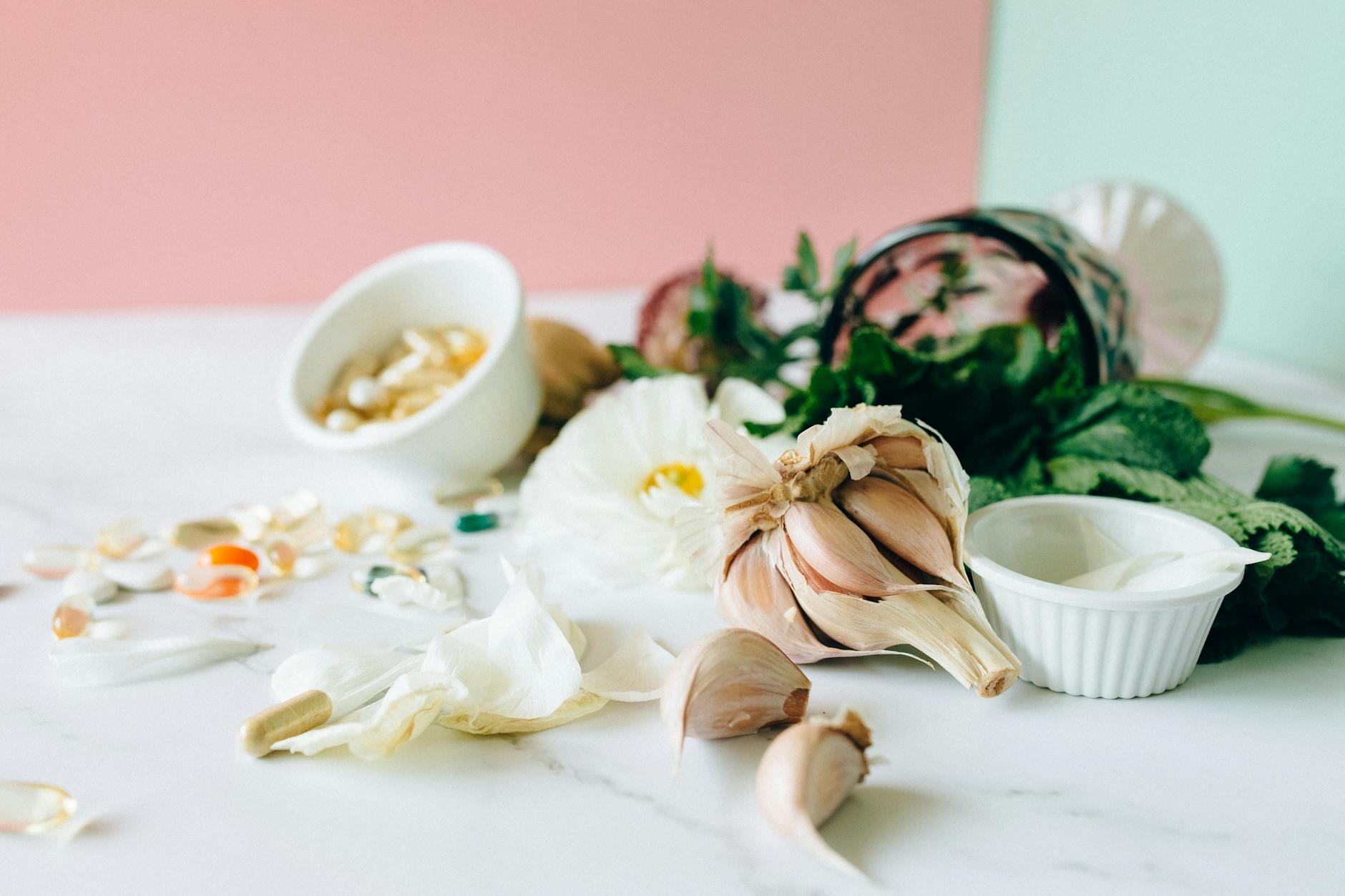 Flat lay of garlic, supplements, and herbs showcasing natural remedies on a marble surface. (Photo by Nataliya Vaitkevich on Pexels)