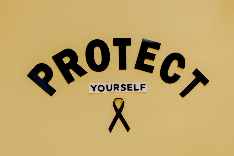 Conceptual awareness image with "Protect Yourself" text and black ribbon on yellow background. (Photo by Tara Winstead on Pexels)
