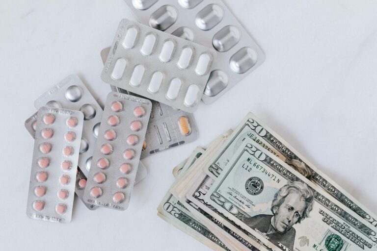 Top view of different blisters of medications and pills composed with heap of paper money (Photo by www.kaboompics.com on Pexels)