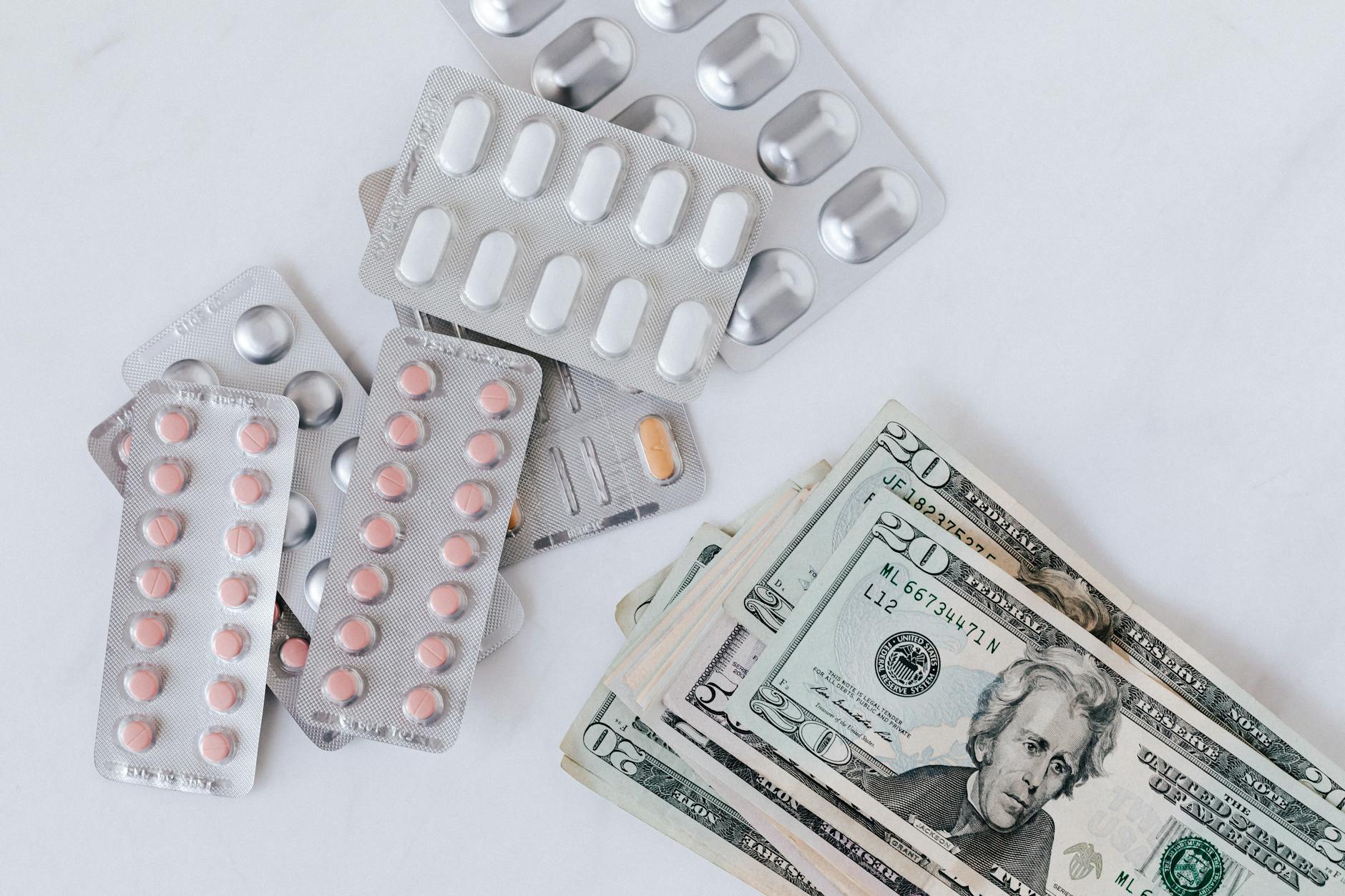 Top view of different blisters of medications and pills composed with heap of paper money (Photo by www.kaboompics.com on Pexels)