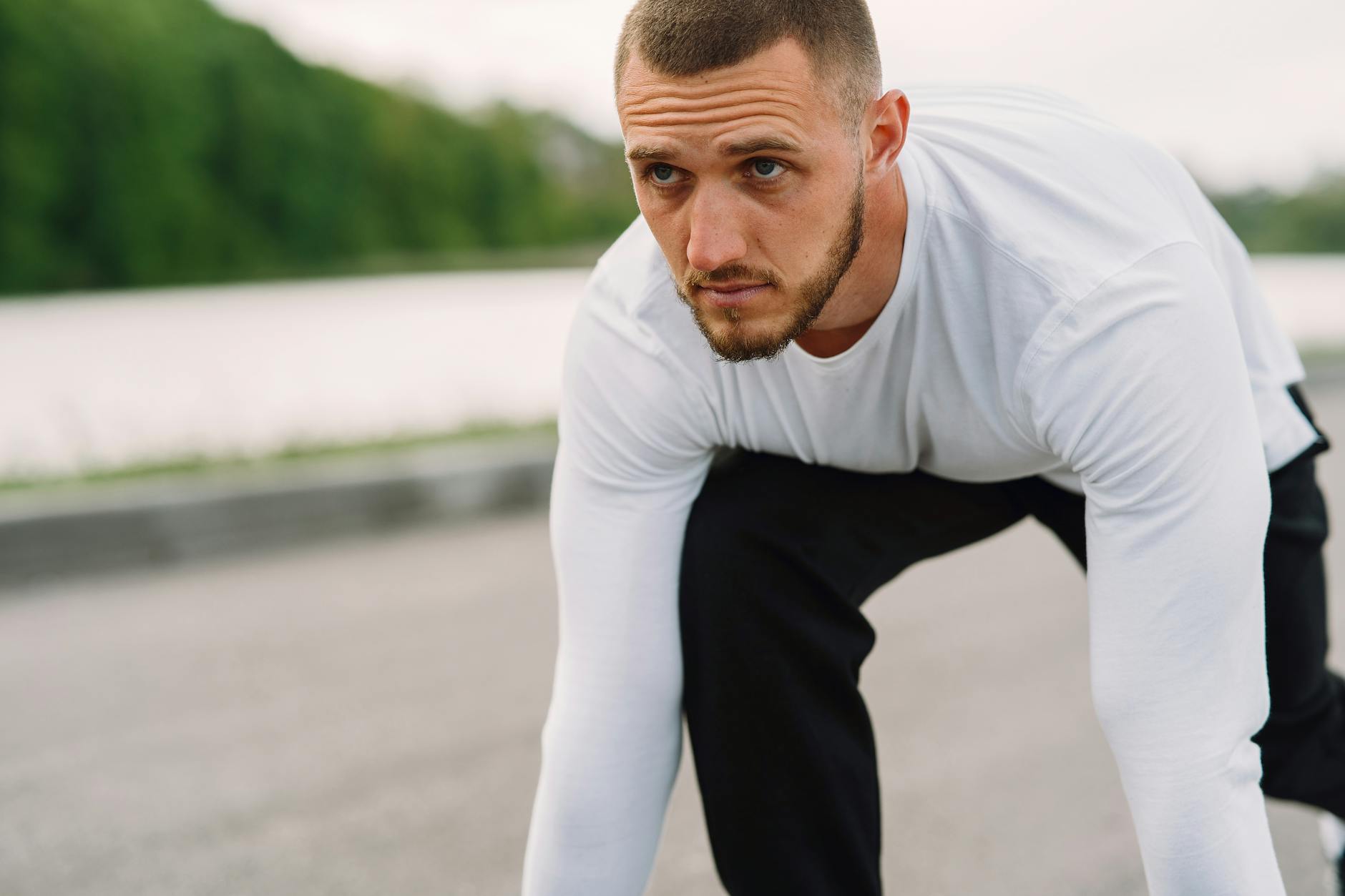 Athletic man in sportswear on a starting line, ready for a sprint workout outdoors. (Photo by Gustavo Fring on Pexels)